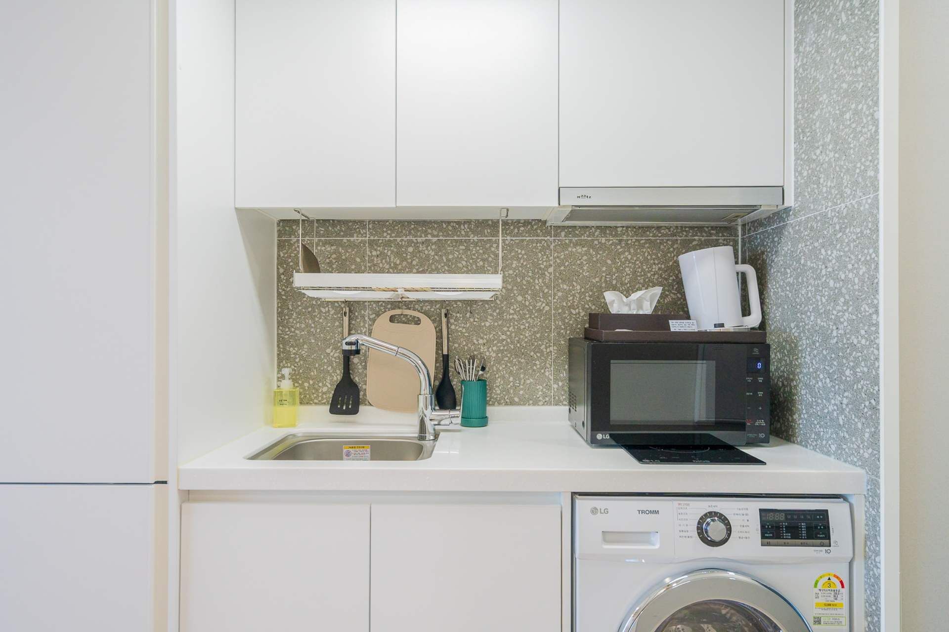Cozinha compacta com pia, micro-ondas e máquina de lavar.