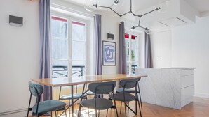 A modern kitchen with a wooden table and four chairs, a marble countertop, and a pendant light fixture.