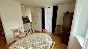 A compact living space with a dining table, chairs, a kitchenette, and a wardrobe.