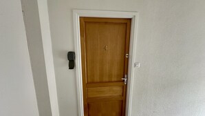 A wooden door with a number '4' above it, a doorbell, and a light switch on the wall.
