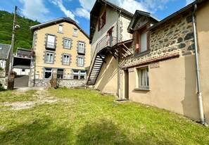 Un edificio con fachada de piedra, una escalera que conduce a un piso superior y un pequeño balcón.