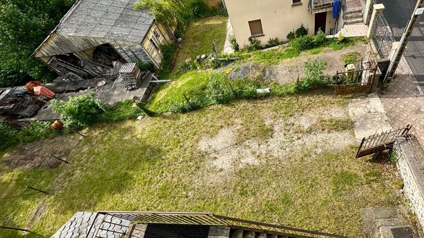 Un quartier résidentiel avec une cour verdoyante, un bâtiment délabré et une maison moderne à deux étages.