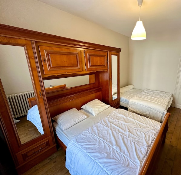Un dormitorio con dos camas individuales, cabeceros de madera y un espejo grande.
