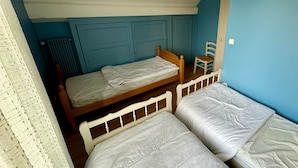 Une chambre de dortoir avec des lits superposés, une chaise et un radiateur.