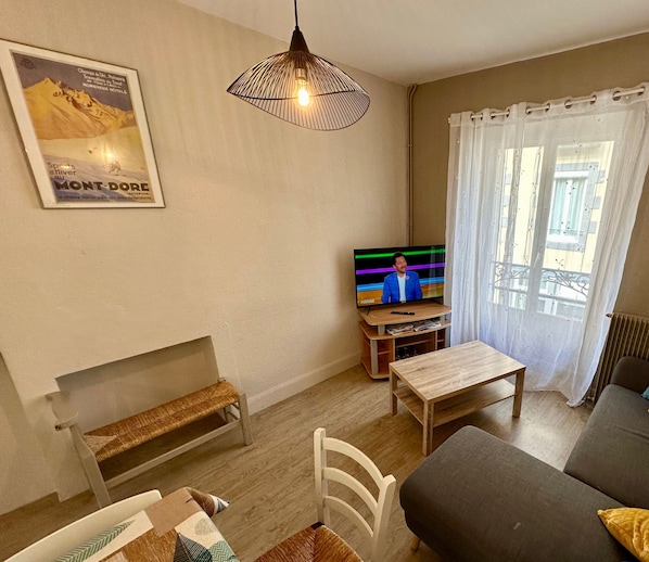 Una sala de estar acogedora con televisor, mesa de madera, banco y sofá.
