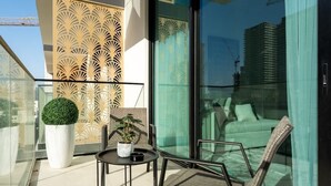 A balcony with a glass door, a potted plant, a small table, and a wicker chair.