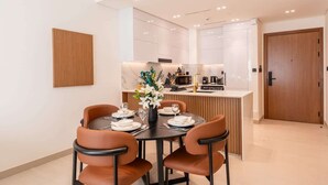 A modern kitchen with white cabinets, a central island, and a dining area with a round table and chairs.