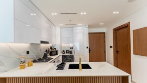 A modern kitchen with white cabinetry, a marble countertop, and a built-in stove.