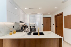 Una cocina moderna con armarios blancos, encimera de mármol y estufa integrada.
