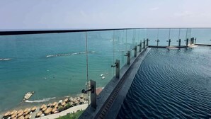 Una piscina con fondo de cristal que ofrece vistas infinitas a un cuerpo de agua con un muelle y barcos.