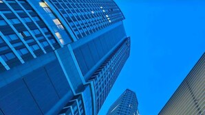 Un edificio moderno con el nombre 'FRONTROW' en su fachada, que presenta un frente de vidrio y un diseño vertical destacado.