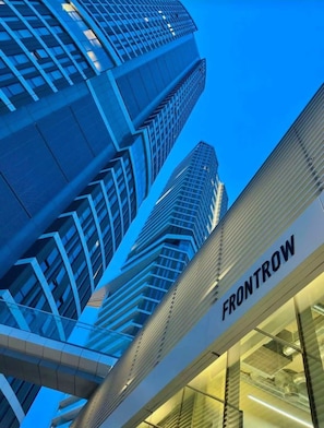 Un edificio moderno con el nombre 'FRONTROW' en su fachada, que presenta un frente de vidrio y un diseño vertical destacado.