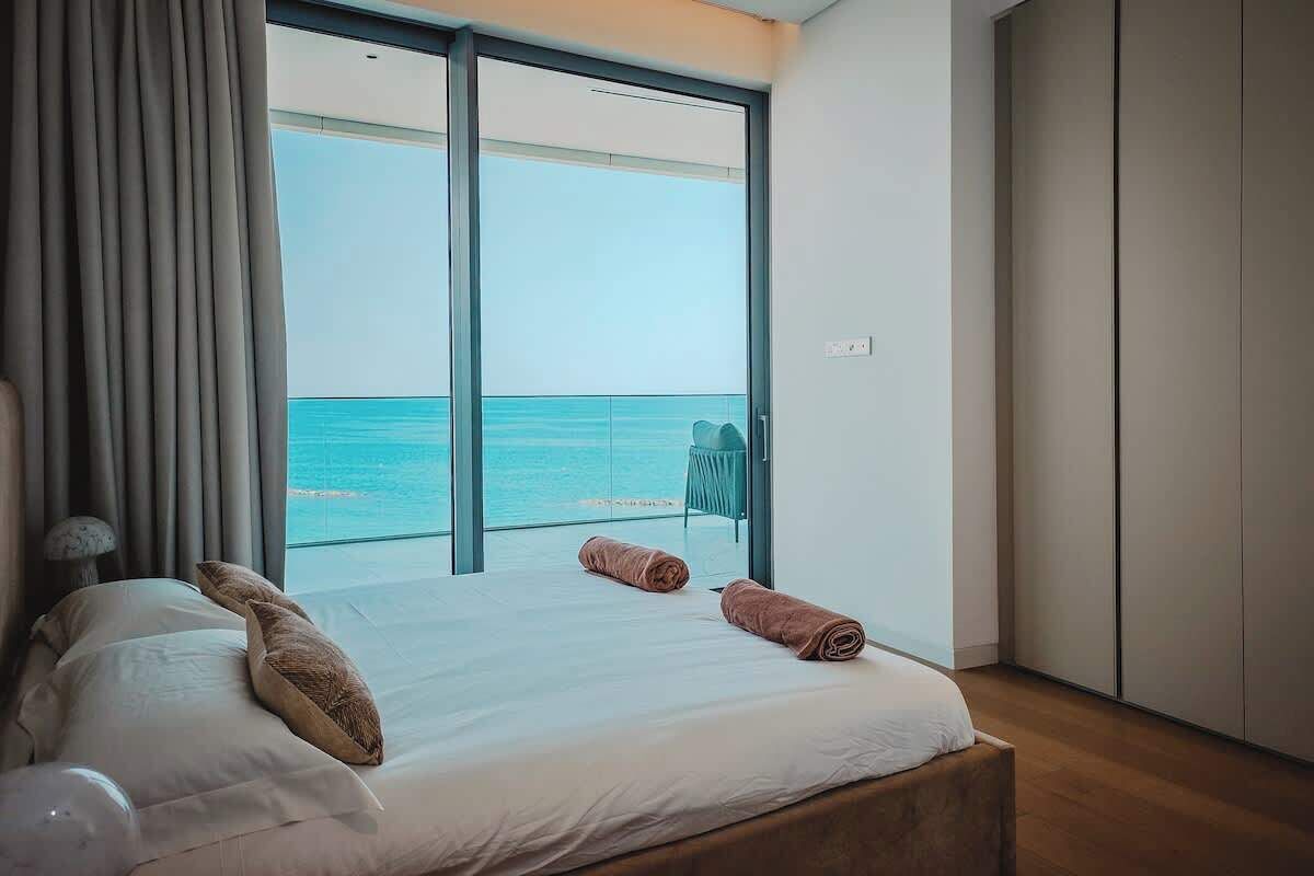 Une chambre avec un grand lit, une vue sur la mer et une porte coulissante donnant sur le balcon.