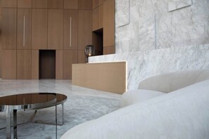 Ein modernes Interieur mit Marmorboden, einem runden Metalltisch und einem schlichten Sofa.