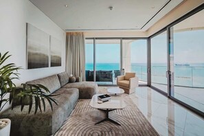 Ein modernes Wohnzimmer mit einer Couch, einem Couchtisch und Meerblick durch große Fenster.