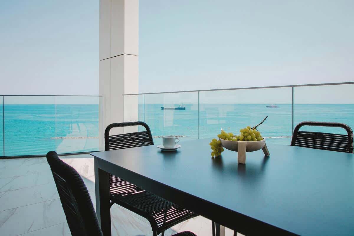 A dining area with a table and chairs, a bowl of grapes, and a cup on the table.