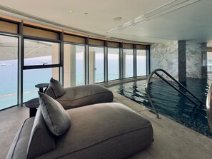 Ein modernes Zimmer mit großem Fenster, Pool und einer Couch.
