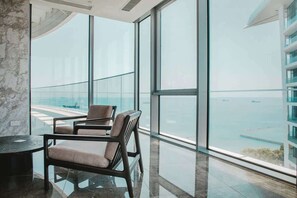 Un intérieur moderne avec de grandes fenêtres, un coin salon avec des fauteuils et une vue sur une étendue d’eau.