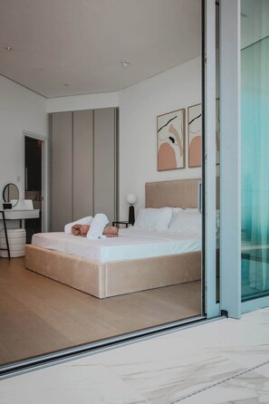 Ein modernes Schlafzimmer mit einem großen Bett, einem Nachttisch, einem Sessel und einem Spiegel.