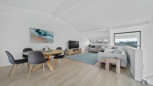 Uma sala de estar moderna com área de jantar, televisão de tela plana e uma grande janela com vista.
