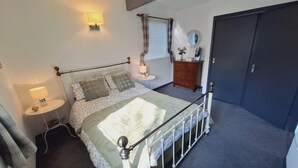 Un dormitorio con cama, lámparas de noche, cómoda, espejo y una puerta.