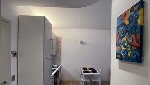 Una cocina compacta con electrodomésticos modernos, un comedor con una pequeña mesa y sillas, y un colorido cuadro abstracto en la pared.