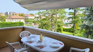 A balcony with a table set for two, overlooking a residential area with houses and trees. - SG Family - Classic Peschiera (Peschiera del Garda)