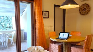 A hotel room with a bed, a laptop on a small table, a chair, and a view of the outside. - SG Family - Classic Peschiera (Peschiera del Garda)