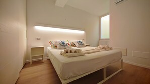 A hotel room with a bed, bedside tables, a window, and a radiator.