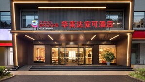 A modern hotel entrance with a glass facade, a sign indicating it's a Ramada by Wyndham hotel, and a welcoming interior visible through the glass doors. - Ramada Encore by Wyndham Kunming Jingkai (Kunming)