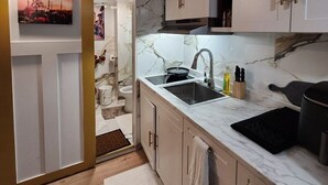Une cuisine de taille réduite, équipée d’un évier, d’une cuisinière et d’un dosseret en marbre.