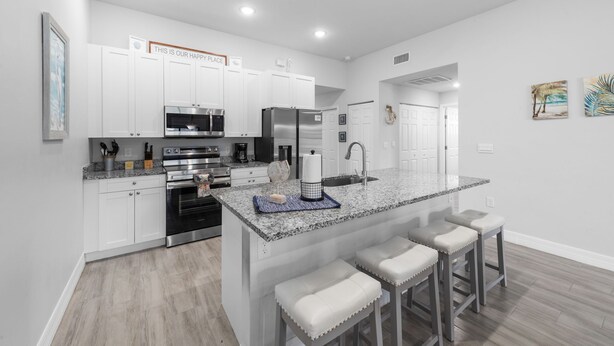 Una cocina moderna con armarios blancos, electrodomésticos de acero inoxidable y encimera de granito.
