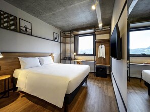 A modern hotel room with a large bed, a desk, a chair, a TV, and a window with a view. - Ibis Balneario Camboriu (Balneário Camboriú)
