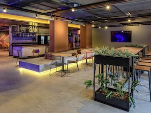 A modern bar area with a neon sign, seating, and a TV screen. - Ibis Balneario Camboriu (Balneário Camboriú)