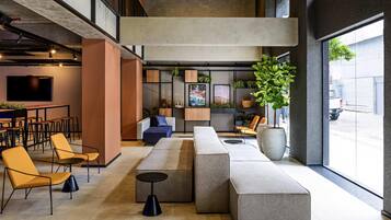 Ein stilvoller Lounge-Bereich mit Sitzgelegenheiten, einer Bar und einem großen Fenster mit Blick auf die Straße.