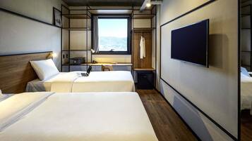 Ett modernt hotellrum med två sängar, en TV, ett skrivbord med en stol, ett fönster med utsikt och en garderob.