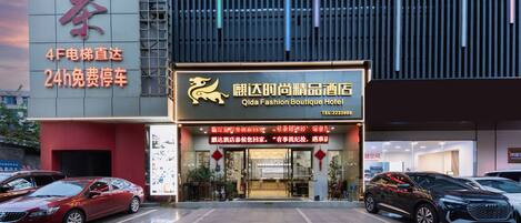 A hotel entrance with a sign for Qida Fashion Boutique Hotel.