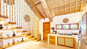 A modern kitchen with bamboo accents, a central island, and a dining area with a view. - Villa Indigo - 5-BDR, huge pool and lush garden (Kecamatan Kuta)