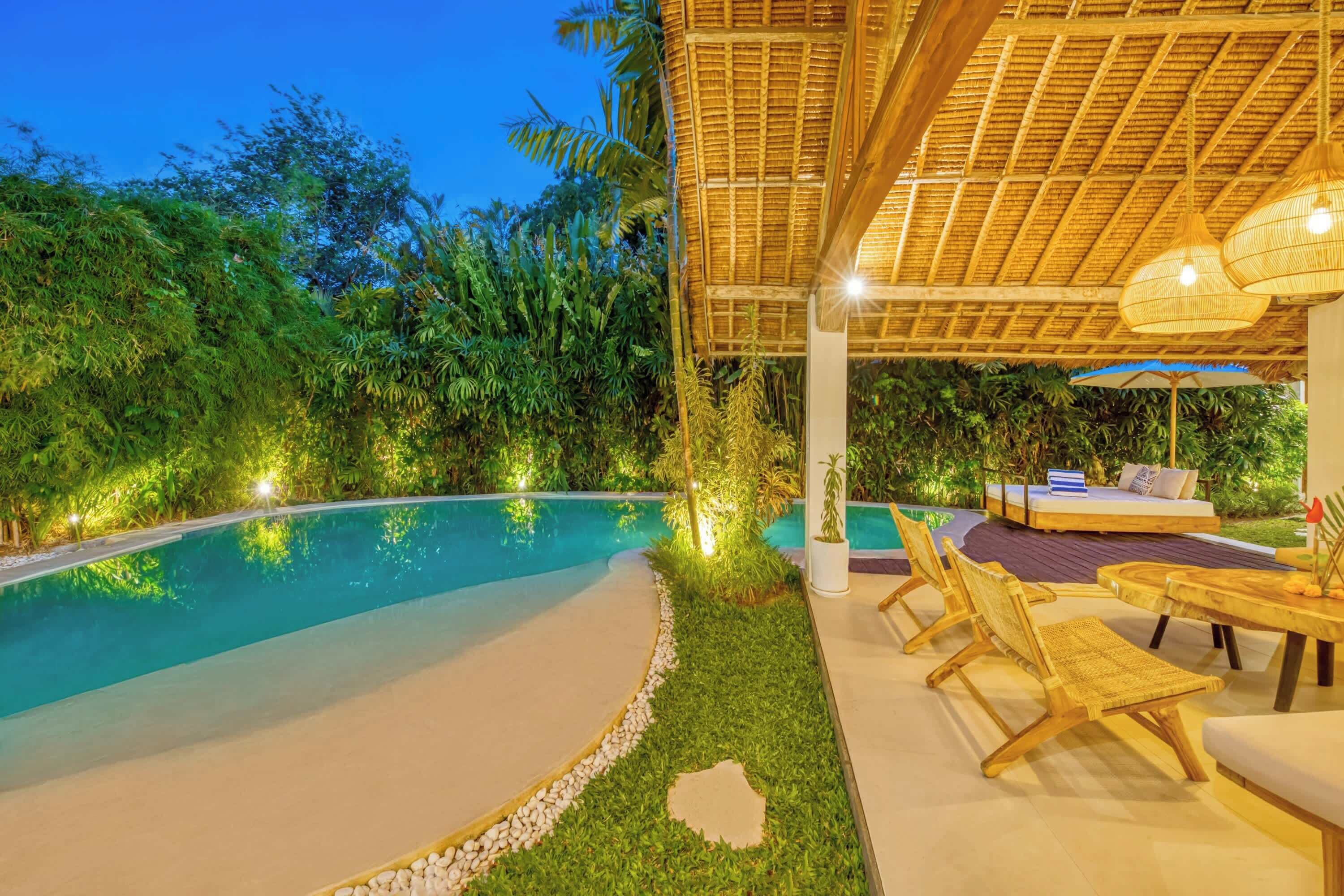 A poolside area with a covered seating area, lounge chairs, and a small table.