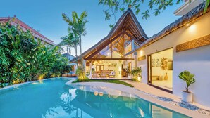 A modern house with a swimming pool, surrounded by lush greenery and a thatched-roof structure. - Villa Indigo - 5-BDR, huge pool and lush garden (Kecamatan Kuta)
