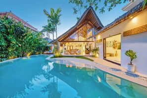 A modern house with a swimming pool, surrounded by lush greenery and a thatched-roof structure. - Villa Indigo - 5-BDR, huge pool and lush garden (Kecamatan Kuta)