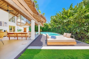 A modern outdoor living space with a pool, a wooden deck, and lush greenery. - Villa Indigo - 5-BDR, huge pool and lush garden (Kecamatan Kuta)