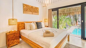 A bedroom with a wooden bed, bedside lamps, a nightstand, and a view of a swimming pool.