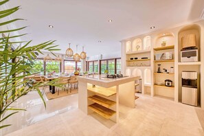 A modern kitchen with a central island, built-in shelves, and a refrigerator.