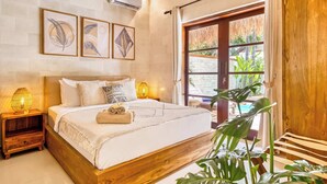 Un dormitorio con estructura de cama de madera, una mesita de noche con lámpara, una obra de arte enmarcada en la pared y vistas a zonas verdes al exterior.