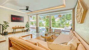 A modern living room with a sofa, a coffee table, and a TV displaying 'NETFLIX'. - Villa Florence - 3BDR Luxury Bali Oasis (Kecamatan Kuta Selatan)