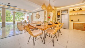 A spacious dining area with a wooden table, wicker chairs, and pendant lighting. - Villa Florence - 3BDR Luxury Bali Oasis (Kecamatan Kuta Selatan)