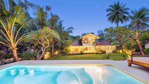 Una casa con piscina, rodeada de vegetación tropical.