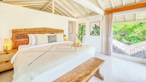 Un dormitorio con una cama grande, cabecera de madera, mesitas de noche, un banco y vistas a zonas verdes.