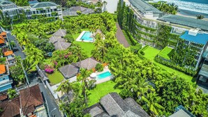 Un resort con piscina, exuberante vegetación y vistas a la playa.